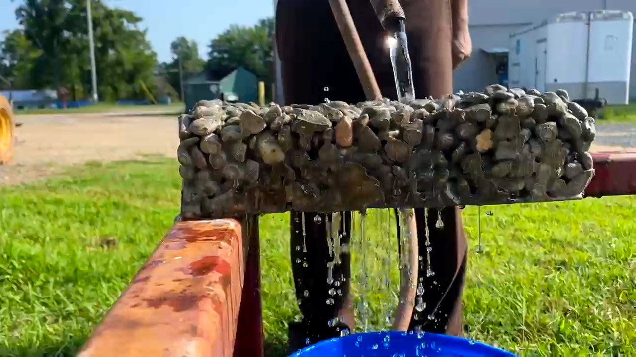 Still image from video of scientist pouring water through a sample of pervious geopolymer concrete.